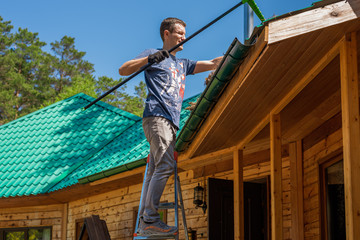 A man cleans the roof in a country house