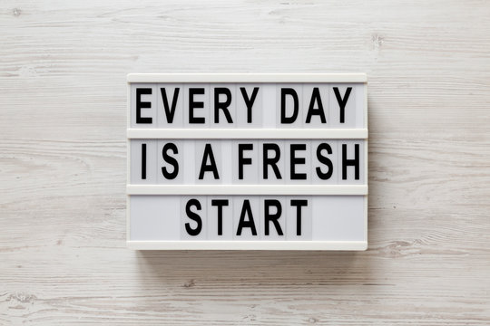 'Every day is a fresh start' words on a lightbox on a white wooden surface, top view. Overhead, from above, flat lay.