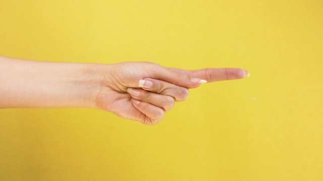 female hand shows on someone and calls to his gestures closeup isolated on yellow background