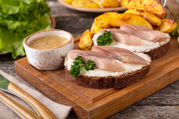 Fototapeta na wymiar Sandwich with herring fillets and baked potato ina wooden board.