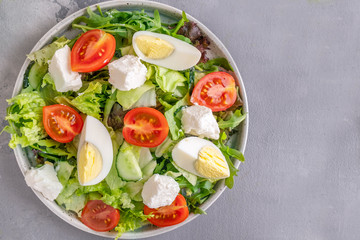 Eggs, tomatoes, cheese and lettuce on a plate. Vegetable salad. Top view, copy space