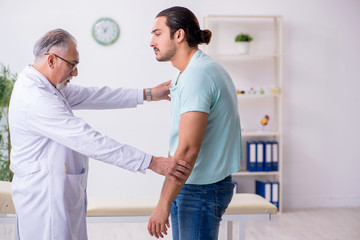 Obraz premium Young back injured man visiting experienced male doctor