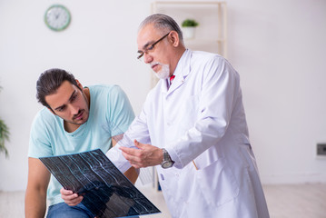 Young back injured man visiting experienced male doctor