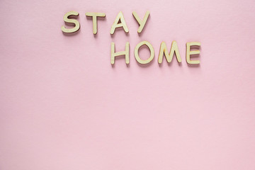 Words stay home made of wooden letters on pink background. Stay at home during pandemic. Top view, copy space