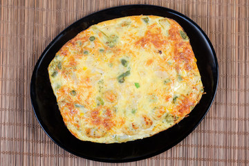 Baked vegetable casserole served on black dish, top view
