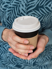 Close up detail shot of woman's hands with black eco take away cup of hot coffee with copy space blank for your advertisement text or design content