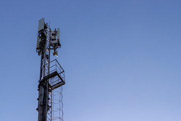 A closeup and detailed view of various GPS, cellphone, 3G, 4G and 5G equipped telecommunication tower as seen on cloudy blue sky with copy space..