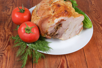 Piece of baked pork on the white dish with vegetables