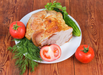 Piece of baked pork on dish with vegetables and greens