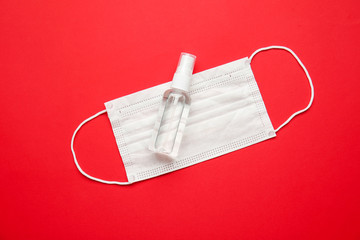 Disinfectant and medical mask on color background