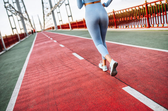 Never Give Up. Female Legs In A Sports Wear And In Runners Sneakers On The Road. Jogging, Running, Marathon