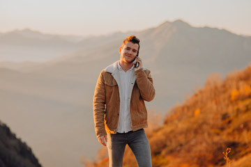 man with phone looking at the camera and smiling in the mountains