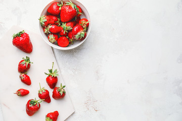 Bowl with ripe strawberry on light background
