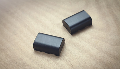 Camera battery on the wooden background.