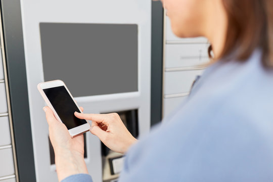 mail delivery and post service concept - close up of woman with smartphone choosing operation on outdoor automated parcel machine's touch screen