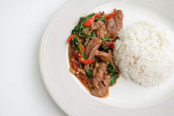 Spicy stir-fried pork basil in a white plate on white table, Traditional thai food