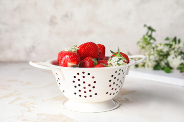 Colander with ripe strawberry on light table