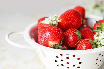 Colander with ripe strawberry on light table, closeup