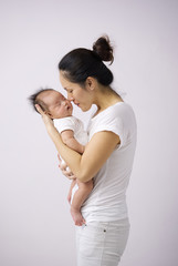 Asian chinese mother carrying her newborn child indoors with pink background