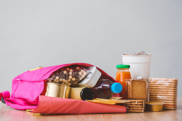 Schoolbag with different products on light background. Concept of Backpack Food Program