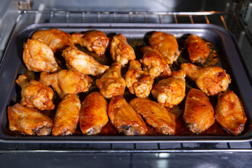 Chicken wings baked on a stainless steel tray in the microwave.