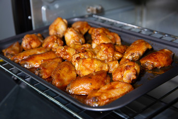 Chicken wings baked on a stainless steel tray in the microwave.