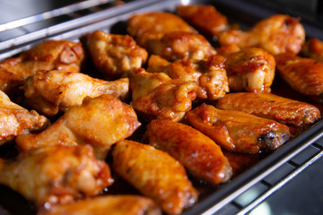 Chicken wings baked on a stainless steel tray in the microwave.