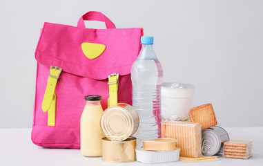 Schoolbag with different products on light background. Concept of Backpack Food Program