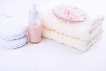 Fototapeta na wymiar Spa relax and bath concept, sea salt, soap, with cosmetics and towels on a white background. A soft cotton towel, sea salt and a sponge for washing. Soft focus free space for text.