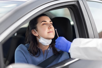 medicine, quarantine and pandemic concept - doctor or healthcare worker in protective gear or hazmat suit with cotton swab making coronavirus test for young woman in her car