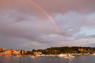 Naklejka na ściany i meble Rainbow in the sky over the town of Rovinj, Croatia, with the Adriatic Sea and some boats sailing
