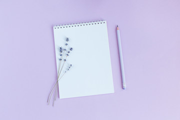 Notebook with blank page, pencil and lavander on a violet background.