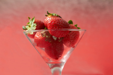 Red sweet ripe strawberries in glass on red background. Healthy organic sweet fruit.