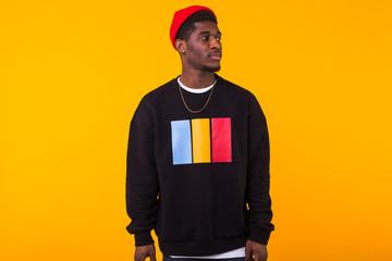 Street fashion concept - Studio shot of young handsome African man wearing sweatshirt against yellow background.