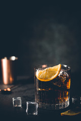 Fresh made Cuba Libre cocktail with brown rum, cola and lemon on wooden background