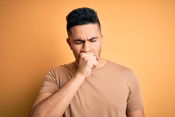 Young handsome man wearing casual t-shirt standing over isolated yellow background feeling unwell...