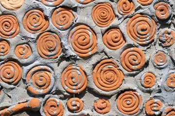 Background fragment of a wall with embedded clay figures: spiral