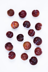 Plums on white background. High angle view of fresh plums. Top view of many plums fruit on white background.