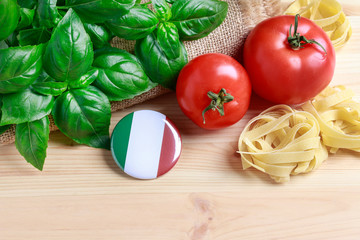 Basil leaves, tomatoes and raw pasta on wooden background.