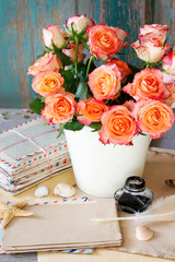 A bouquet of roses, stack of letters, inkwell and pen. Postcard motif.