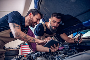 Two mechanics in uniform are working in auto service.