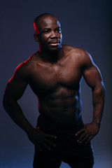 Fototapeta na wymiar Handsome dark-skinned man posing in red-blue neon and showing muscles of a naked torso
