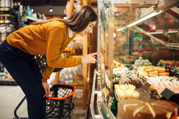 Young woman choosing cakes in grocery store