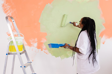 Pretty young african american woman with painting roller indoors. Redecoration, renovation, apartment repair and refreshment concept.