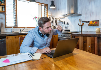 Attractive young business man on computer working from home feeling stressed, tired and overwhelmed