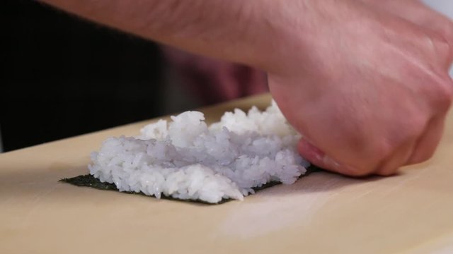 Sushi chef preparing rice for sushi roll