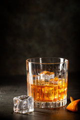 Glass of scotch whiskey with ice cubes on black background