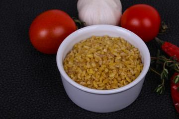 Raw bulgur in the bowl with tomatoes and garlic