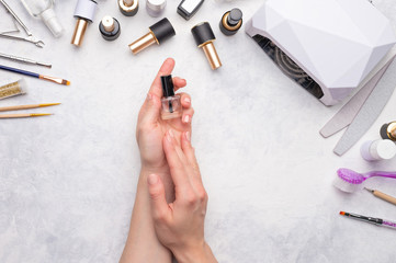 Nail care and care. Girl holds gel polish on a white background with tools for nail care. Advertising of nail salon and female beauty salon.