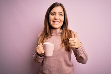 Young blonde woman drinking a cup of coffee over pink isolated background happy with big smile doing ok sign, thumb up with fingers, excellent sign